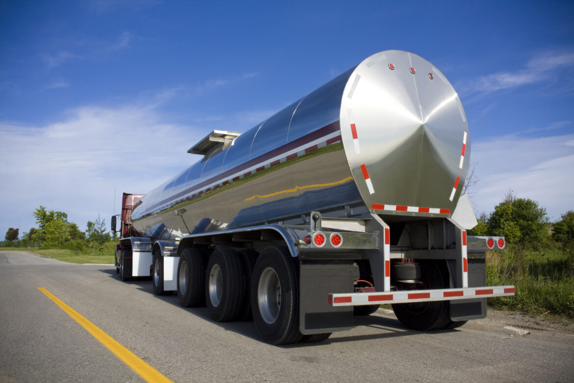 Silver fuel tanker parked on the road fuel tanker delivering inventory as part of supply chain logistics